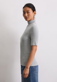 Szary, krótki rękaw turtleneck z dopasowanym fasonem i prążkowaną fakturą, w połączeniu z dżinsami o wysokim stanie.