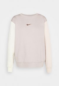 Ljusrosa sweatshirt med långa ärmar i en färgblockdesign, med en liten brun Nike-logotyp på bröstet och ribbade muddar.