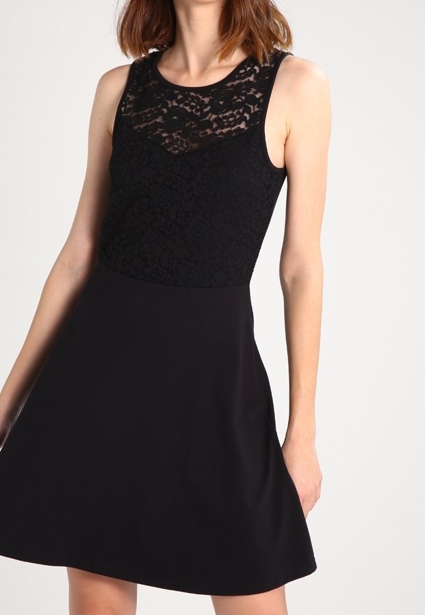 Robe noire avec un corsage en dentelle et une jupe unie. Design sans manches avec encolure arrondie. Texture lisse sur toute la surface.