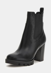 Stivale alla caviglia in pelle nera con tacco a blocco alto, pannelli laterali elasticizzati e dettagli in rilievo sul colletto e sui lati. Suola con battistrada spesso.