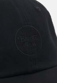 Fekete pamut sapka lekerekített formával és texturált felülettel. Sötét cérnával hímzett kör alakú logo a "Brixton" felirattal.
