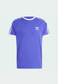 Fioletowa koszulka z białymi akcentami, z okrągłym dekoltem i krótkimi rękawami. Trzy białe paski na każdym ramieniu; małe logo na piersi.