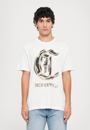 Hvit bomulls t-skjorte med et stort svart og gull grafisk design med teksten "JUST CAVALLI." Korte ermer og løs passform.