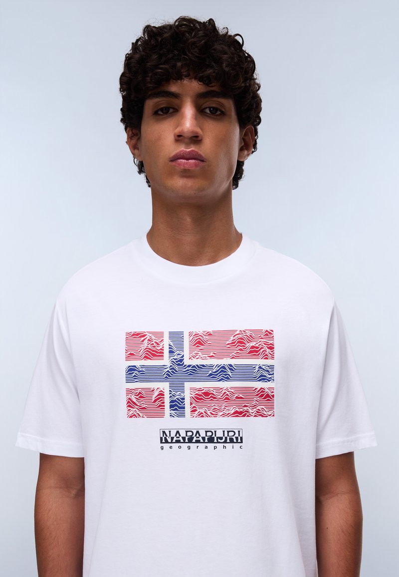 Biała koszulka bawełniana z stylizowaną grafiką norweskiej flagi w czerwonym i niebieskim kolorze, z falistymi liniami oraz napisem "NAPAPIJRI geographic" poniżej.
