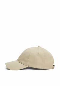Cappellino da baseball beige con visiera curva, tessuto testurizzato e un piccolo logo ricamato sul lato. Cinturino regolabile sul retro.