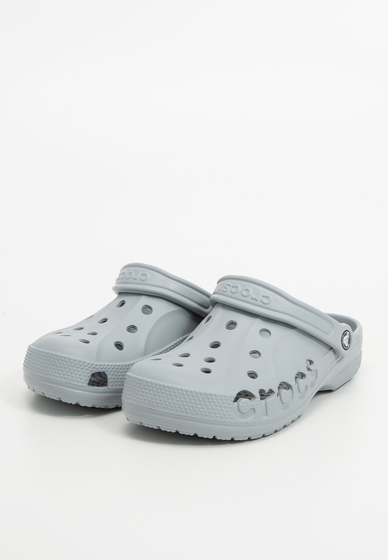 Un par de zuecos Crocs en gris claro con agujeros de ventilación y correas ajustables en el talón, mostrados sobre un fondo blanco.
