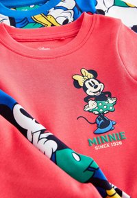 Camicia in cotone rossa con una grafica di Minnie Mouse in una gonna a pois. Presenta maniche blu e decorate con personaggi Disney.