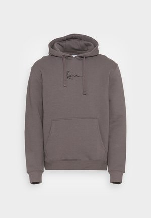 Sweat à capuche gris foncé avec poche avant et cordons, avec un petit texte de signature noir sur la poitrine.