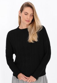 Schwarzer Grobstrick-Pullover mit geripptem Halsausschnitt und Bündchen, strukturierten Mustern und einer lässigen Passform. Der Stoff wirkt weich und warm.