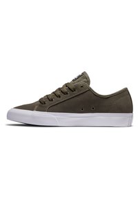 Zapatillas de ante verde oliva con suelas de goma blanca, cinco agujeros para los cordones y una etiqueta negra en la lengüeta. Punta redondeada y diseño minimalista.