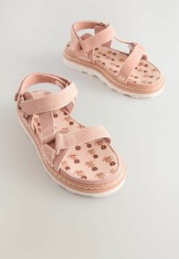 Sandales en suède rose avec des brides ajustables, semelle en caoutchouc blanche et semelles intérieures à motif floral. Comprend une semelle rembourrée pour le confort.