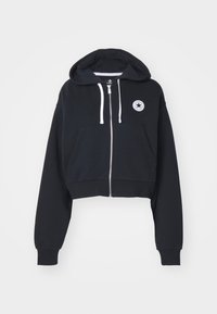 Cropped black hoodie in cotton blend, featuring a front zip, two side pockets, white drawstrings, and a circular logo patch on the left chest.