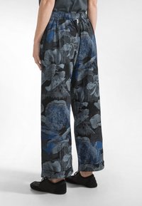 Spodnie w kwiatowy wzór na czarnym tle, z niebieskimi i szarymi kwiatami. Mają elastyczny pas i szerokie nogawki.