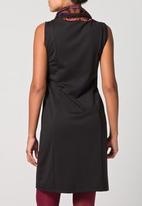 Robes sans manches noires avec une silhouette ajustée, présentant une écharpe à motifs colorés au niveau du col et une texture de tissu lisse.