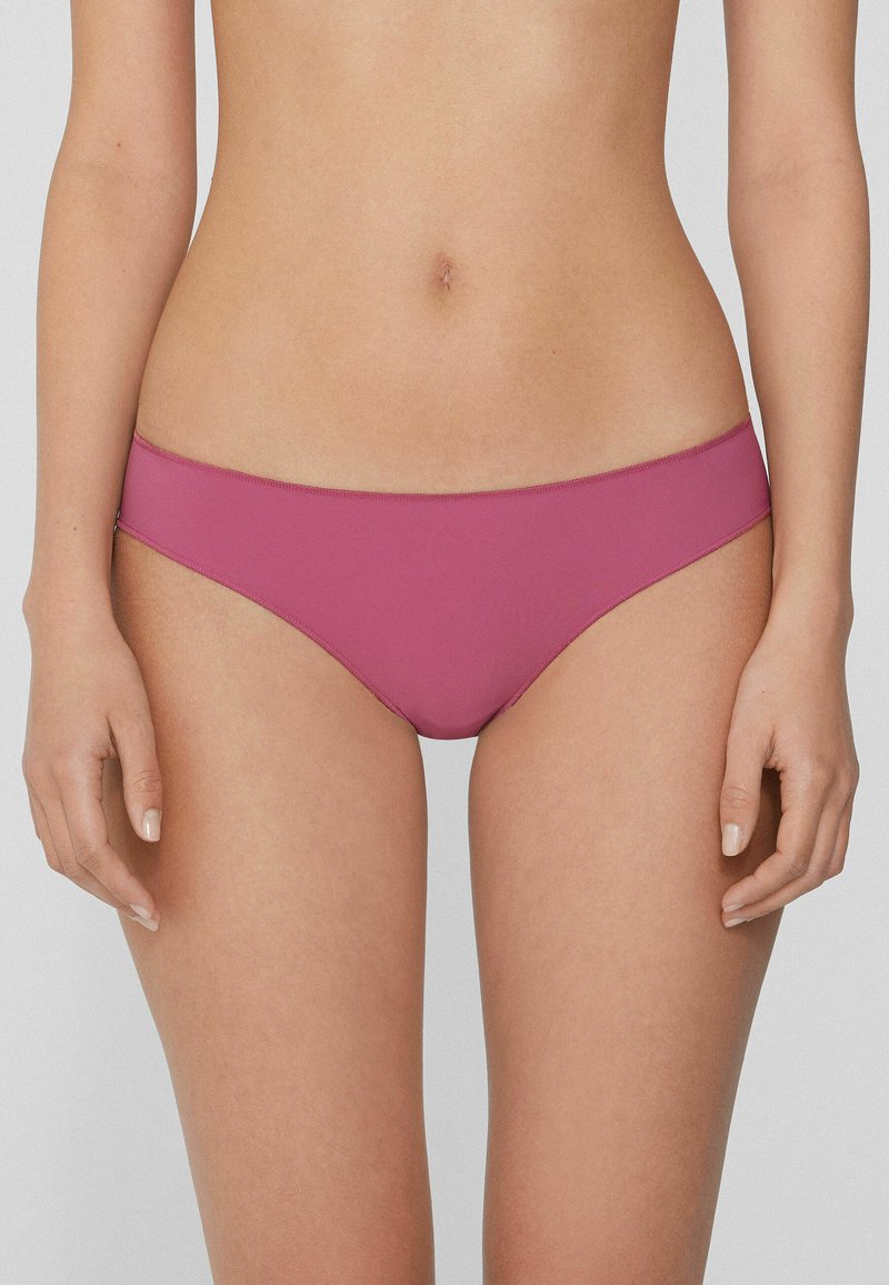 Bañador de bikini rosa con una textura suave y cobertura mínima. Presenta una cinturilla limpia y un diseño elegante sin patrones visibles ni herrajes.