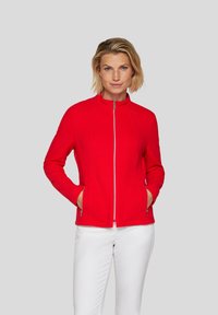 Red zip-up jacket with a textured pattern, high collar, and side pockets, paired with white pants.