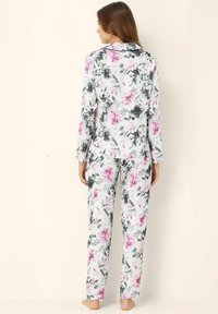 Květnatý pyžamový set s bílým podkladem a růžovými a šedými květy, dlouhými rukávy a košilí na knoflíky, doplněný o odpovídající kalhoty.