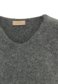 Grå stickad tröja med en mjuk textur, med en V-ringning. Etiketten visar "MARTA" och är fäst nedanför kragen.