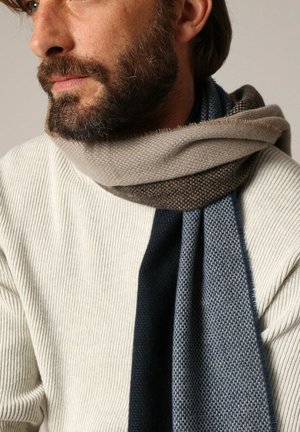 Gebreide sjaal met een verloopontwerp in beige, donkerbruin en donkerblauwe tinten. Zachte textuur, om de nek gewikkeld.