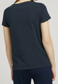 Tummansininen lyhythihainen t-paita pyöreällä pääntiellä, valmistettu sileästä puuvillakankaasta. Ominaisuuksiin kuuluu suora leikkaus ja huomaamaton etiketti sivussa.