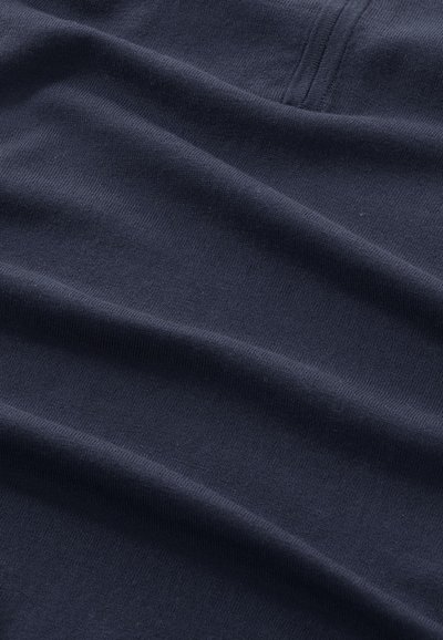 Marineblauwe katoen stof met een gladde textuur, met subtiele ribbelpatronen en zacht gekreukte plooien, die een zachte draperingseffect vormen.