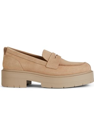 Mocassins en daim beige avec un bout arrondi, des coutures proéminentes et une semelle en caoutchouc épaisse dotée de rainures pour une meilleure traction.