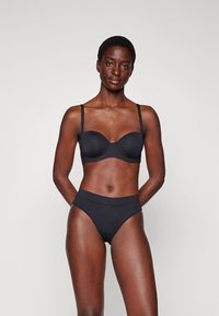 Zwarte beugelbh met gladde stof en verstelbare bandjes, gecombineerd met hooggesneden bijpassende slips, beide met een naadloos ontwerp.