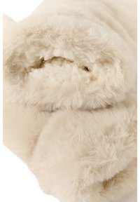 Soft beige sheepskin fabric rolled up, showing dense wool fibers inside and smooth soft outer fur texture.