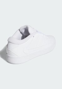 Vit sportskor med en slät läderöverkant, vadderad krage och snörning. Har perforerade detaljer och en texturerad gummisula.