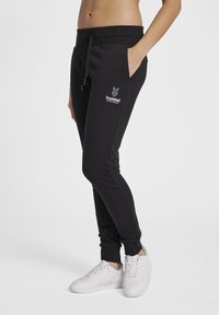 Svarta sweatpants med elastisk midja och dragsko, med den vita "hummel"-logotypen och sidofickor. Slim fit med manschetter vid anklarna.
