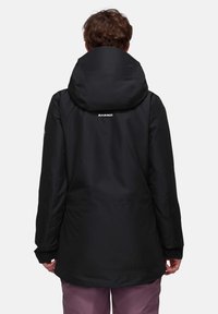 Schwarze wasserdichte Jacke mit Kapuze, langen Ärmeln und einem Logo auf dem Rücken. Das Material wirkt glatt ohne sichtbare Muster oder Akzente.