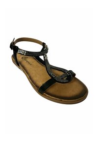 Sandalia negra con cuentas de plata decorativas, correa ajustable al tobillo y suela plana marrón. Superficie texturizada y diseño tipo tiras.