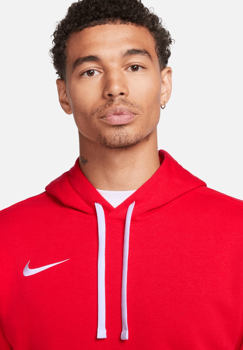 Rode hoodie met witte trekkoorden en een Nike-logo aan de bovenkant aan de linkerkant. Het materiaal lijkt zacht met een gladde textuur en een casual pasvorm.