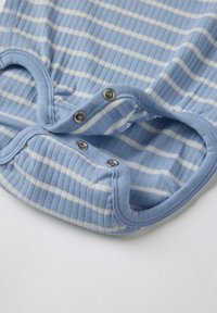 Vaaleansininen raidallinen puuvillahaalari, jossa on lyhyet hihat, nepparit alaosassa ja pehmeä ribbaitu rakenne.