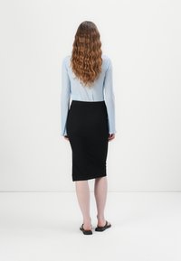 Light blue ribbed long-sleeve top paired with a black knee-length pencil skirt, featuring a textured fabric and fitted silhouette.
