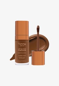 Brun concealeren i en klar flaske med et metallisk bronsekork. Inkluderer en doe-foot applikator og en fargeprøve av produktet på en overflate.