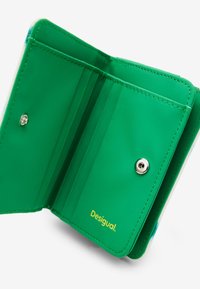 Grüne synthetische Geldbörse mit mehreren Kartenfächern, Druckknopfverschluss und geprägt Logo. Glatte Textur mit kontrastierenden Nähdetails.