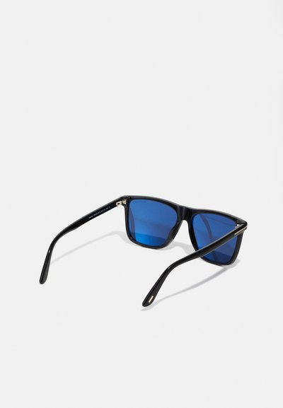 Occhiali da sole neri con montatura quadrata e lenti sfumate blu. Presentano un materiale plastico liscio, bracci neri sottili e sottili accenti metallici.