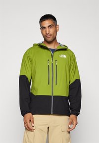 Kurtka typu windbreaker w jasnym zielonym i czarnym kolorze z zamkiem z przodu, kapturem i dwiema kieszeniami na zamek na piersi. Posiada elastyczne mankiety i logo.