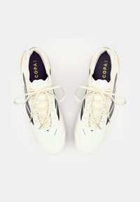 White athletic shoes with a textured surface, black side stripes, and light-colored laces. Features a cushioned insole with 'COPA' branding.