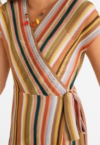 Gestreiftes Strickkleid in mehreren Farben mit einem Wickeldesign, kurzen Ärmeln und einem Stoffband in der Taille. Die Streifen bestehen aus erdigen Tönen und Pastellfarben.