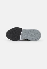 Semelle de chaussure de sport noire et grise avec une surface en caoutchouc texturé. Présente des grips circulaires pour une traction et un schéma de couleurs divisé.