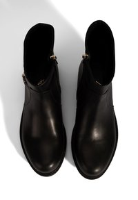 Zwarte leren enkelboots met een gladde textuur, voorzien van een ronde neus en goudkleurige ritsen aan de zijkanten. Stitchingdetail langs de zool.