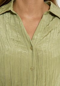 Camicia verde chiaro con bottoni, realizzata in tessuto stropicciato, con colletto, superficie testurizzata e piccoli bottoni lungo la finta.