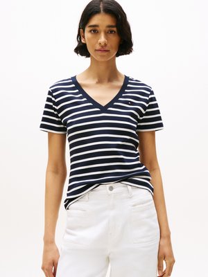 Marineblå og hvid stribet V-hals t-shirt lavet af bomuld, med korte ærmer og en afslappet pasform, parret med hvide jeans.