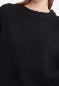 Maglione nero con finitura testurizzata, scollo rotondo e maniche raglan, realizzato in materiale morbido per il massimo comfort.