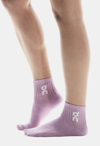 Calzini sportivi lilla con bordo a costine, logo "on" in bianco, vestibilità aderente. Tessuto liscio, design a caviglia bassa adatto per uso casual o sportivo.
