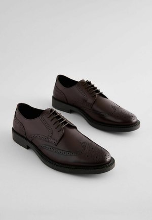 Brown leather lace-up dress shoes with brogue detailing, smooth texture, rounded toe, and a contrasting black sole.