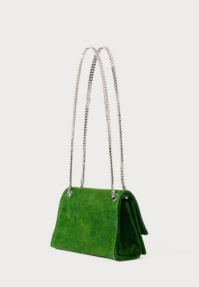 Zelena usnjena torbica s srebrnim dvojni rameni trakovi, pravokotne oblike in strukturiranimi stranicami na belem ozadju.