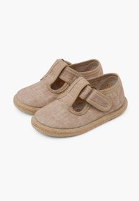 Tan fabric shoes with a woven jute sole, featuring a Velcro strap and round cutouts. Smooth texture with contrasting stitching detail.